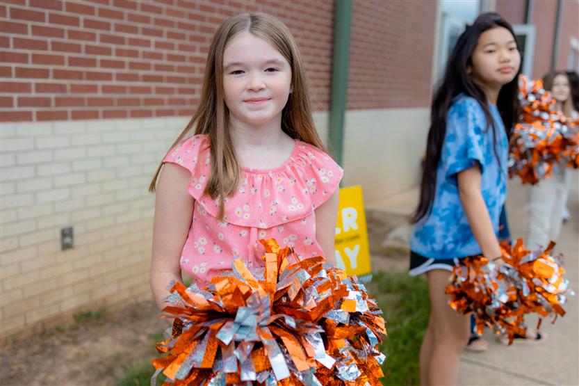 A girl smiles while holding pompoms